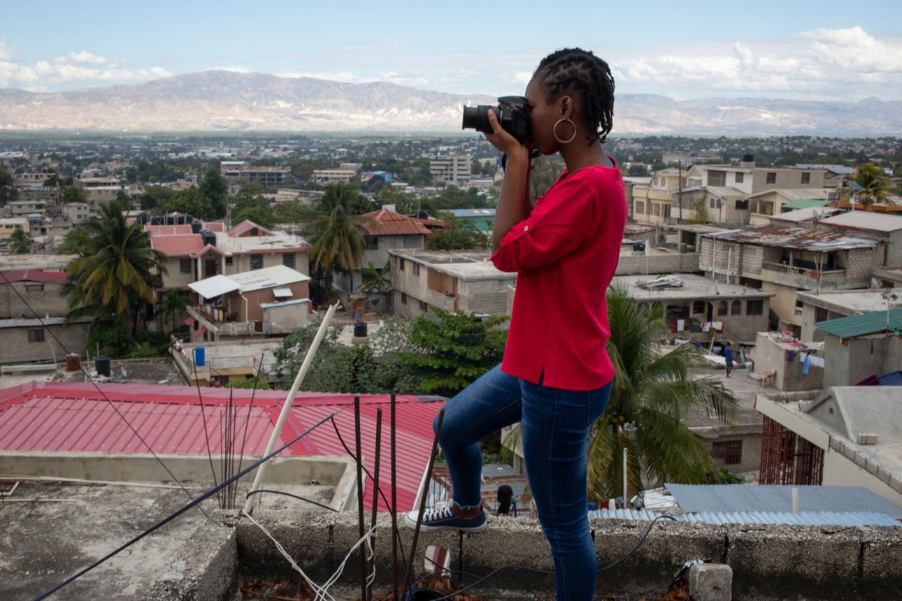 Une photographe haïtienne en train de photographier Port-au-Prince depuis un toit