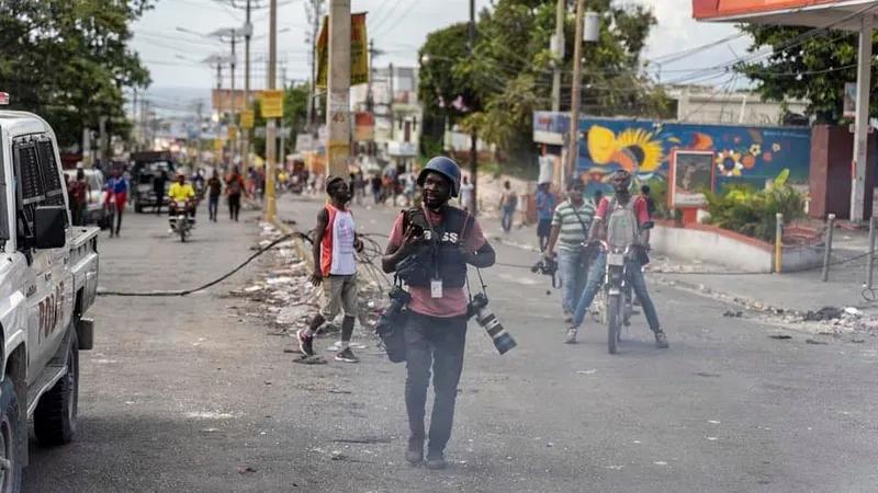 Un reporter photographe casqué et équipé dans une rue de Port-au-Prince